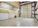 Bright, airy garage featuring large roll-up door, concrete floor, and convenient shelving at 300 Carol Ann Dr, Edgewater, FL 32132