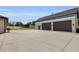 Spacious garage with large doors, exterior lighting, and a concrete driveway surrounded by well-maintained landscaping at 3055 Wolf Branch Rd, Mount Dora, FL 32757