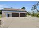 Detached three car garage with dark wood doors and blue trim and large concrete driveway at 3055 Wolf Branch Rd, Mount Dora, FL 32757