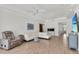 Open living room showcasing a white sectional sofa, recliners, and wood-look tile flooring at 3055 Wolf Branch Rd, Mount Dora, FL 32757