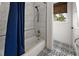 A modern bathroom features marble tile walls, patterned tile floors, and a blue shower curtain at 6905 Clayton St, Mount Dora, FL 32757