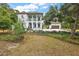 Elegant two-story white home with a charming veranda and lush landscaping on a well-maintained lawn at 6905 Clayton St, Mount Dora, FL 32757