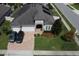 Aerial view showcasing a well-maintained home with a three-car garage, stone accents, and lush landscaping at 2504 Cavender Creek Rd, Minneola, FL 34715