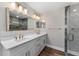 Bathroom featuring double sinks with modern lighting and shower with glass doors at 10033 Canterbury Dr, Leesburg, FL 34788