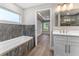 Bathroom with marble tile, bathtub, white vanity, gold fixtures and wood floor at 10033 Canterbury Dr, Leesburg, FL 34788