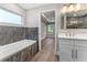 Bathroom with marble tile, bathtub, white vanity, gold fixtures and wood floor at 10033 Canterbury Dr, Leesburg, FL 34788