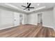 Spacious bedroom with wood floors, tray ceiling, and doorways to the kitchen and bathroom at 10033 Canterbury Dr, Leesburg, FL 34788