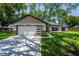 Charming single-story home featuring a two-car garage, well-manicured lawn, and neutral exterior paint at 10033 Canterbury Dr, Leesburg, FL 34788