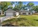 Charming single-Gathering home featuring a modern garage door and well-manicured lawn and landscaping at 10033 Canterbury Dr, Leesburg, FL 34788