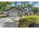 Inviting single-story home with modern design, a spacious driveway, and manicured front yard landscaping at 10033 Canterbury Dr, Leesburg, FL 34788