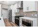 Modern kitchen featuring white cabinets, quartz countertops, stainless steel appliances, and stylish pendant lighting at 10033 Canterbury Dr, Leesburg, FL 34788