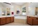 Bathroom featuring dual vanities, a soaking tub with tile surround, and a window for natural light at 105 E Blue Water Edge Dr, Eustis, FL 32736