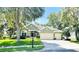 Charming single-story home with a well-manicured lawn, mature trees, and a three-car garage at 105 E Blue Water Edge Dr, Eustis, FL 32736