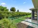 View of the backyard featuring a lush green lawn, green chain link fence, and tropical landscaping at 10977 Se 169Th Ln, Summerfield, FL 34491