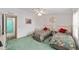 Comfortable bedroom with floral bedding, soft green carpet, and access to the bathroom at 1109 Paradise Dr, The Villages, FL 32159