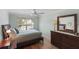 Bedroom with hardwood floors, ceiling fan, wooden dresser, a large window, and soft, comfortable pillows at 1140 Eureka Mill Run, The Villages, FL 32162