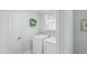 Well-lit laundry room includes modern washing machine and dryer and a decorative wreath at 1140 Eureka Mill Run, The Villages, FL 32162