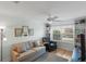 Bright living room featuring a comfortable couch, armchair, built-in shelving, and large window at 1140 Eureka Mill Run, The Villages, FL 32162