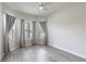 Bright bedroom with wood-look floors, a ceiling fan, and three windows with stylish gray curtains at 1268 Patterson Ter, Lake Mary, FL 32746