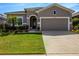 Charming home with a two-car garage, well manicured landscaping and green lawn at 13304 Magnolia Valley Dr, Clermont, FL 34711