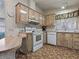 Well-lit kitchen featuring wood-toned cabinets, modern appliances, and decorative wallpaper at 1437 Apache Cir, Tavares, FL 32778