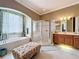 Well-lit bathroom with tub, glass shower, double sink vanity and decorative ottoman seating area at 1473 Lakemist Ln, Clermont, FL 34711