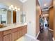 Bathroom with wooden vanity, marble countertop, sink, mirror and hallway leading to other rooms at 1473 Lakemist Ln, Clermont, FL 34711