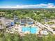 Aerial view of the community pool with palm trees, lounge chairs, and a clubhouse at 1473 Lakemist Ln, Clermont, FL 34711