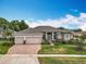 Stunning single-story home with a three-car garage, manicured lawn, and vibrant landscaping at 1473 Lakemist Ln, Clermont, FL 34711