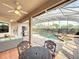 Enclosed patio with fans, dining table, outdoor kitchen with a pool in the background at 1473 Lakemist Ln, Clermont, FL 34711