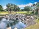 Scenic pond featuring a rock waterfall, lush greenery, and a tranquil water feature on the golf course at 1473 Lakemist Ln, Clermont, FL 34711