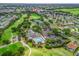 Aerial view of a clubhouse with a pool, with a golf course, tennis courts, and residential area nearby at 17349 Se 76Th Flintlock Ter, The Villages, FL 32162