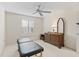 Bedroom with plantation shutters, ceiling fan, carpet, dresser, and a massage table at 17349 Se 76Th Flintlock Ter, The Villages, FL 32162
