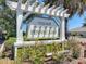 Welcome to Village of Pennecamp! Beautiful community sign with lush landscaping and vibrant greenery at 1842 Lake Ridge Dr, The Villages, FL 32162