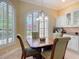 Bright dining area with large windows, plantation shutters, and a view of the kitchen with white cabinets at 1842 Lake Ridge Dr, The Villages, FL 32162