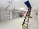 View of spacious three car garage, with epoxy floors and a pull-down ladder to access attic storage space at 1842 Lake Ridge Dr, The Villages, FL 32162
