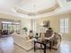 Elegant living room with coffered ceiling, neutral decor, and sliding glass doors to the lanai at 1842 Lake Ridge Dr, The Villages, FL 32162