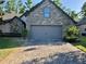 Stone-accented home exterior with paved driveway, complemented by lush greenery at 1893 Banning Beach Rd, Tavares, FL 32778