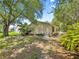 The side of this home has a well kept lawn, exterior air conditioning unit, and tropical landscaping of plants and trees at 2102 Estevez Dr, Lady Lake, FL 32159