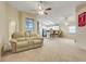 Open-concept living area with carpet flooring, ceiling fans, and kitchen view at 2136 Fish Eagle St, Clermont, FL 34714