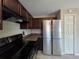 Beautiful kitchen with dark cabinets, stainless steel refrigerator, and black appliances at 222 Locust Ln, Ocala, FL 34471