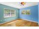 Bright bedroom featuring hardwood floors, two windows, and a unique ceiling fan at 2400 N Griffin Dr, Leesburg, FL 34748
