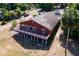 Aerial view of a red two-story home featuring a spacious deck with white railings and a sprawling lawn at 2400 N Griffin Dr, Leesburg, FL 34748