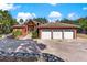 Charming exterior with red facade, 3-car garage, stone accents, and circular driveway at 2400 N Griffin Dr, Leesburg, FL 34748