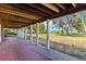 A covered brick porch with trees and grass in the distance at 2400 N Griffin Dr, Leesburg, FL 34748