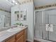 Bathroom featuring a vanity with solid surface countertop, large mirror, and glass-enclosed shower at 2450 Kingstree Pl, The Villages, FL 32162