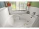 Bathroom featuring a garden tub with natural light and neutral tile surround at 25129 Riverwalk Dr, Leesburg, FL 34748