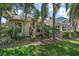 Exterior view of the home showcasing the screen enclosed lanai and lush tropical landscaping at 25129 Riverwalk Dr, Leesburg, FL 34748