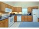Bright kitchen featuring light wood cabinetry, stainless steel appliances, and white tiled floors at 2539 Caithness Way, Clermont, FL 34714