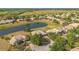 Aerial view of homes in a tranquil community surrounding a pond, with lush landscaping and clear blue skies at 2641 Meadow View Ct, Kissimmee, FL 34746